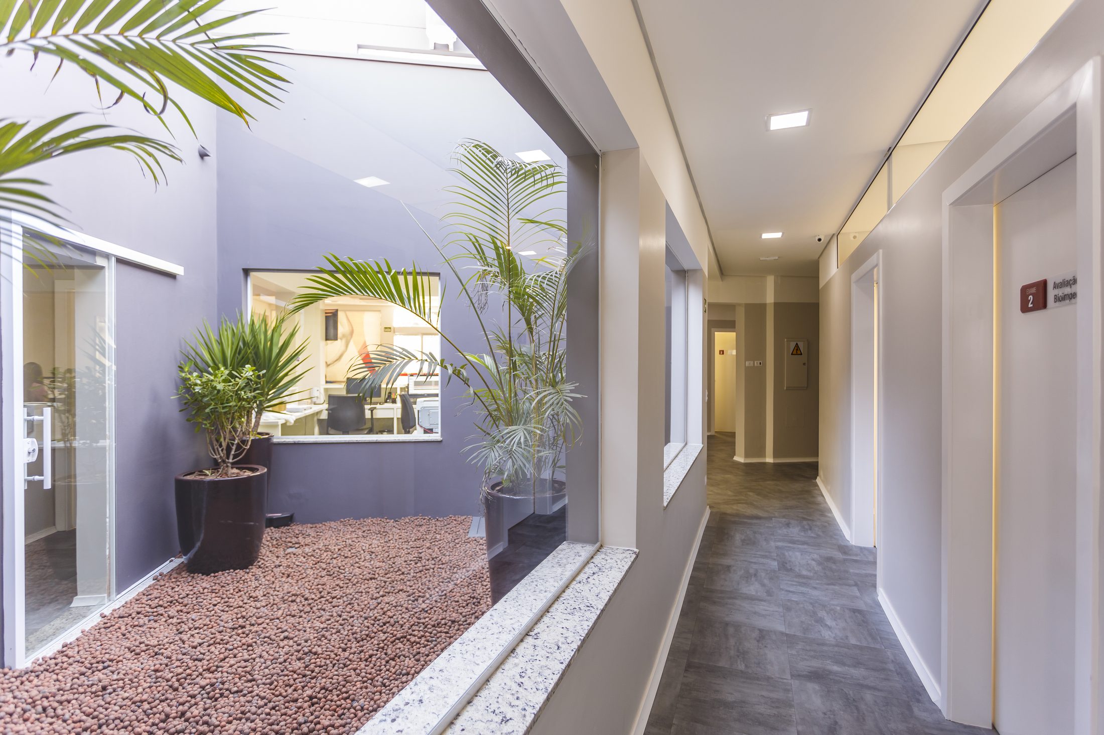 Corredor da clínica com jardim interno de pedras